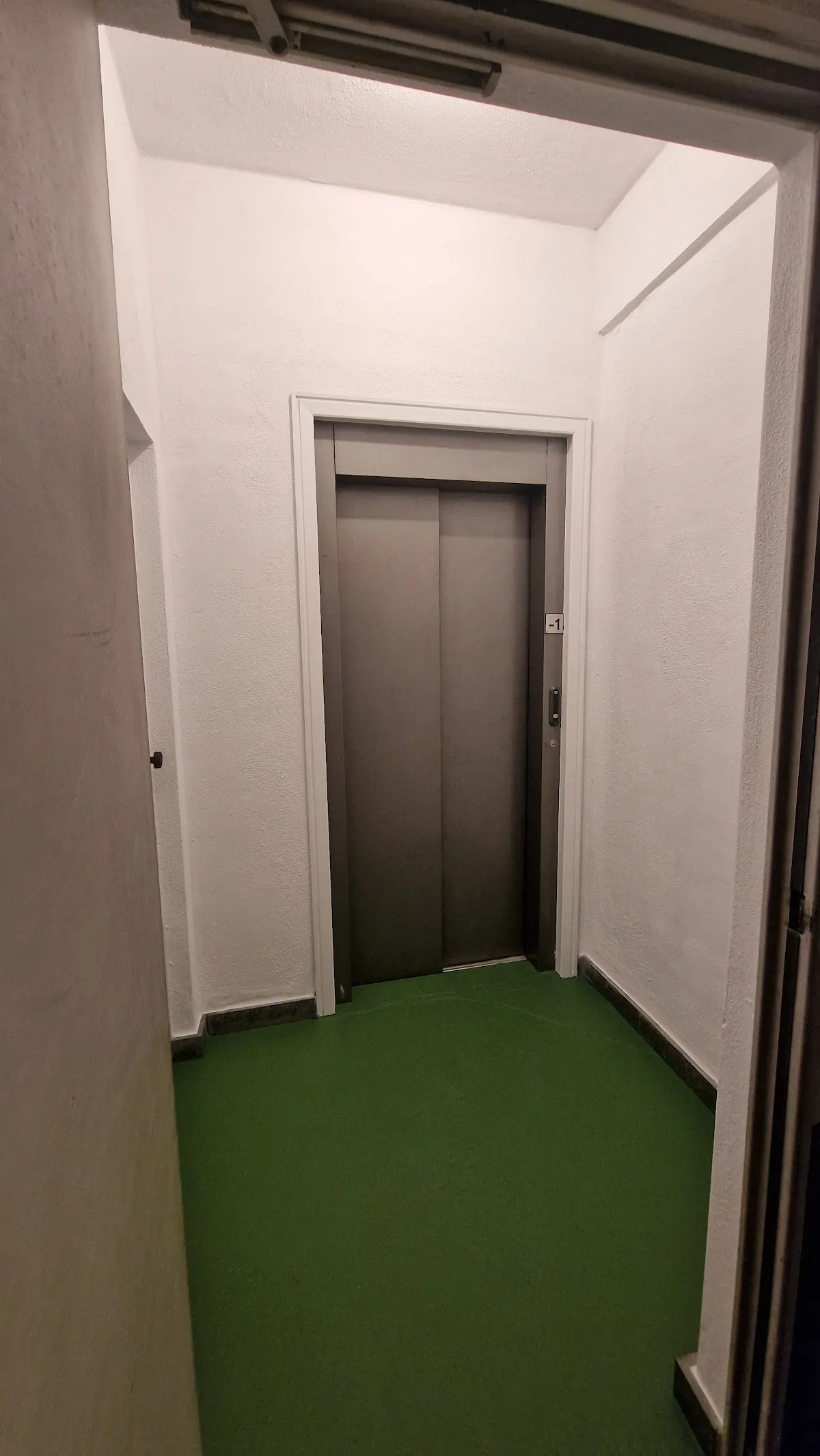 Rellano con puertas de ascensor y suelo verde, en una imagen de Kadi Pintores