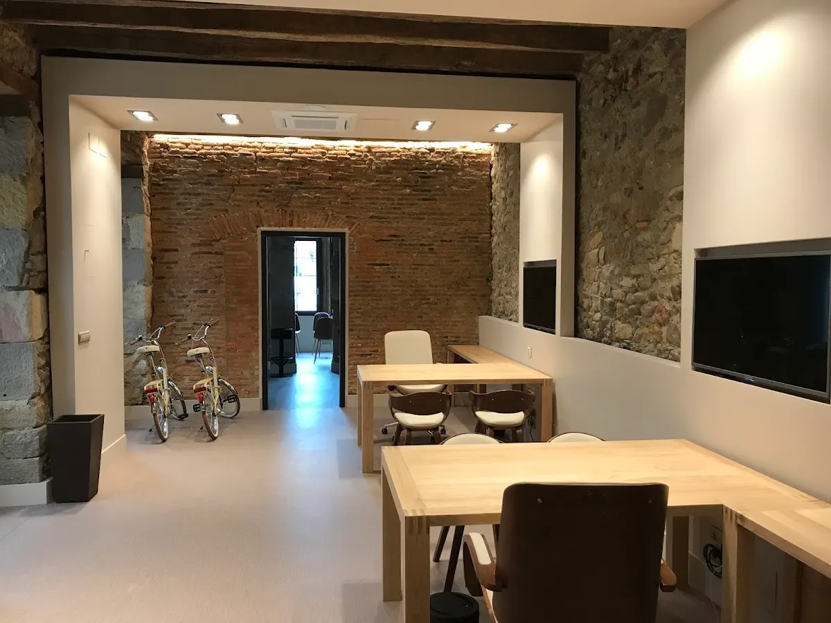 Espacio interior de KBIA Inmobiliaria con mesas y paredes de piedra
