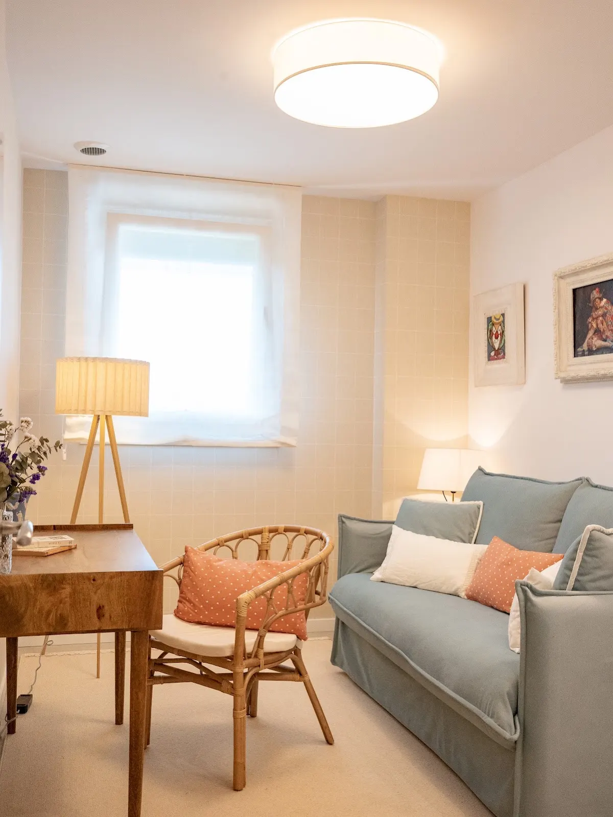 Salón con sofá azul claro, sillón de mimbre y lámpara de pie.
