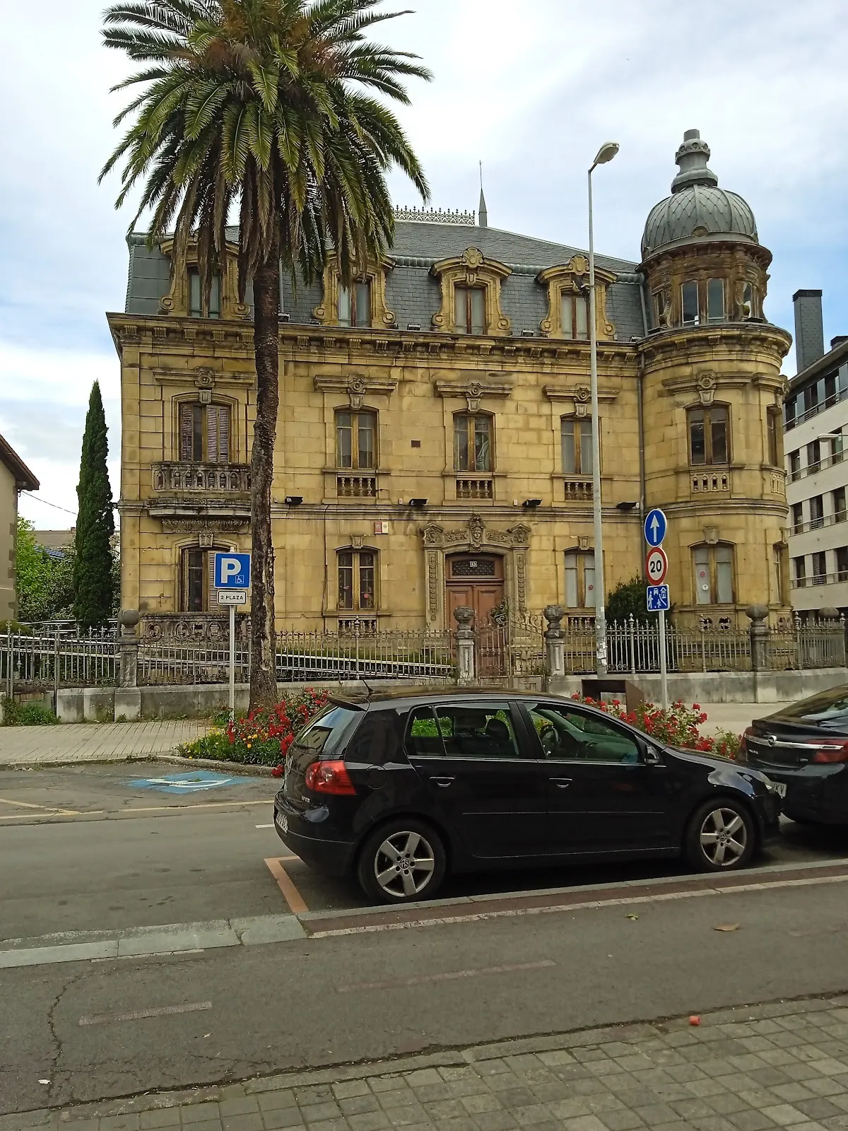 Vista exterior de un edificio histórico en Durango, con una palmera y coches en primer plano.