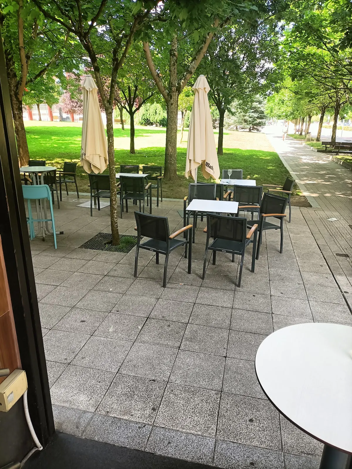 Terraza exterior de Kuttun Gastrobar, con mesas y sillas junto a una zona arbolada.