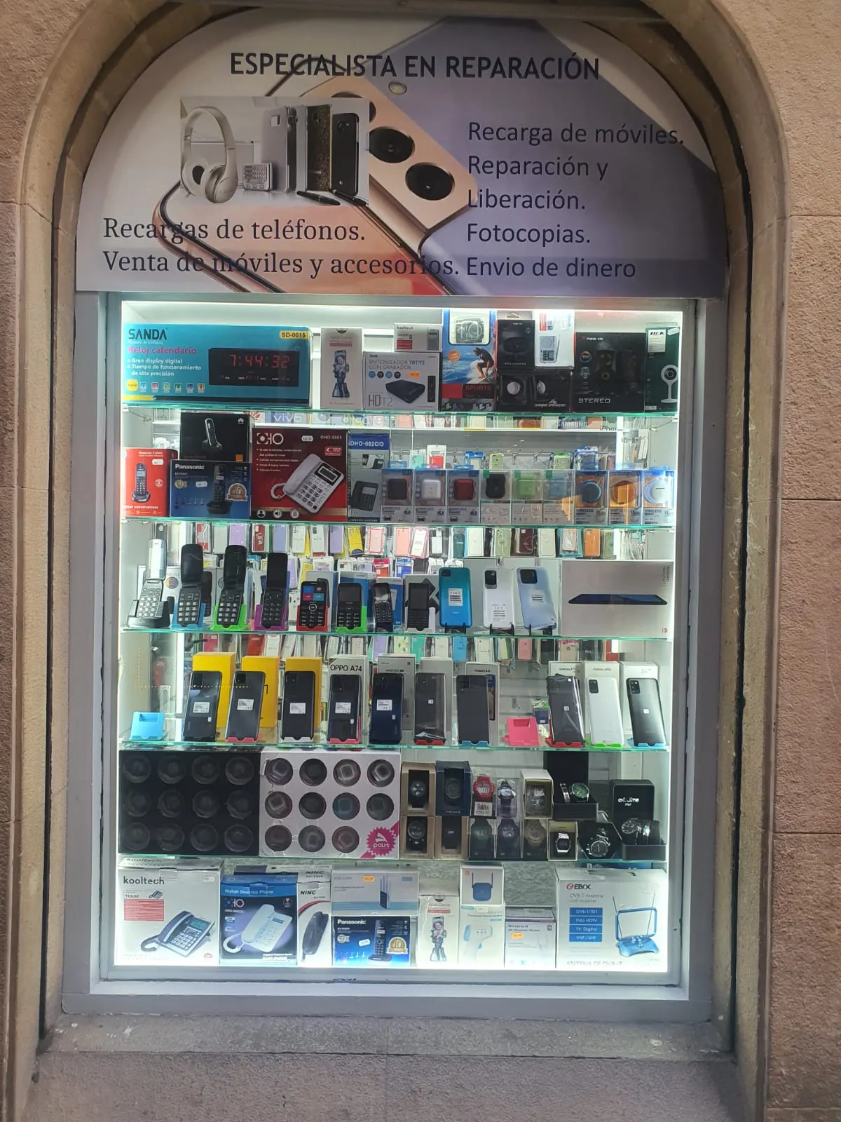 Escaparate de LA CASA DEL MOVIL con accesorios y carteles de reparación de móviles.