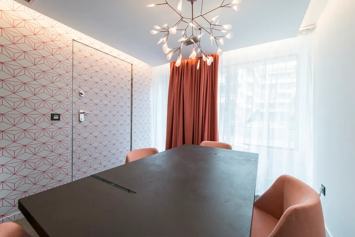 Sala de reuniones de LEGALYMAS con una mesa oscura y sillones rosados.