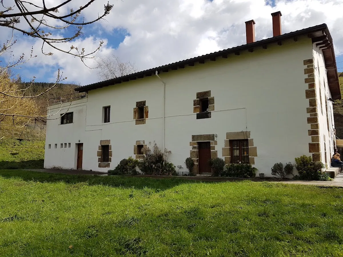 Fachada blanca de Lekun Etxea junto a una zona verde