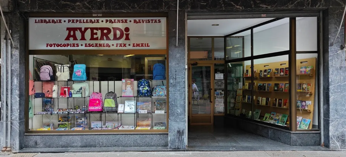 Escaparate y entrada de Librería Ayerdi en Amorebieta-Etxano, con mochilas y artículos de papelería.