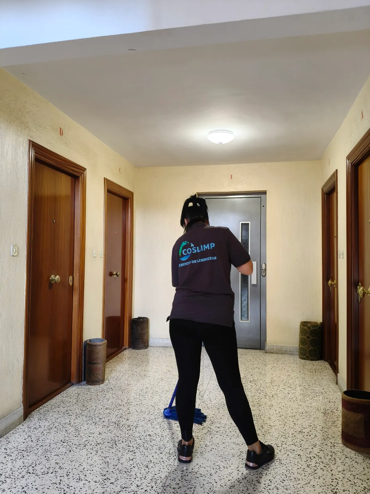 Una trabajadora friega el suelo de un portal; Limpiezas COSLIMP GARBIKETAK.