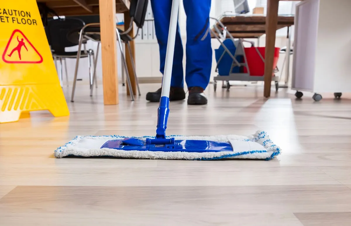 Mopa limpiando el suelo de una sala con mesas y sillas