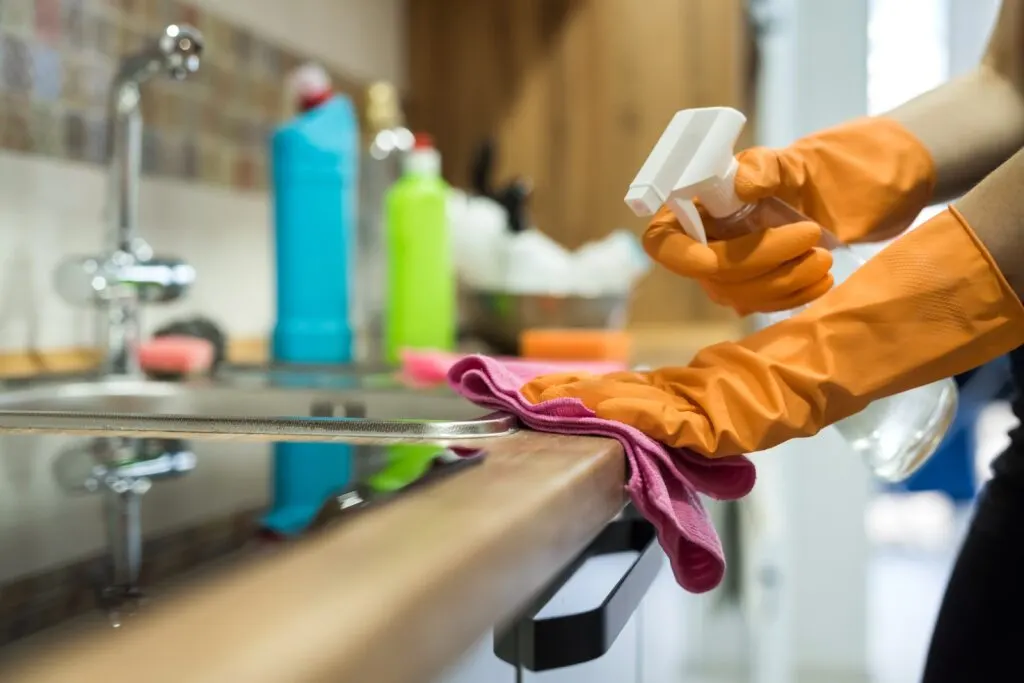 Manos con guantes limpiando una superficie con un paño, imagen asociada a Limpiezas Garbitu
