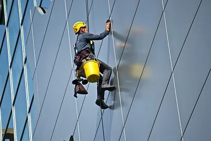 Profesional de Limpiezas y Mantenimientos Alonso trabajando en altura sobre una fachada acristalada