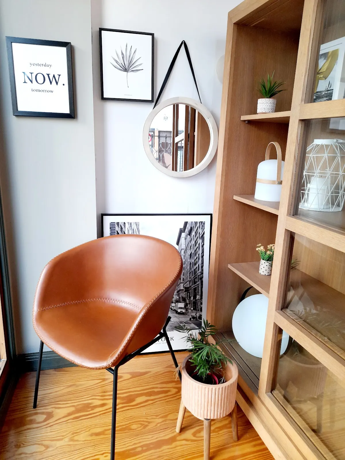 Rincón decorado con una silla de cuero, plantas y estantería de madera en Loiro Decoración de Interiores.