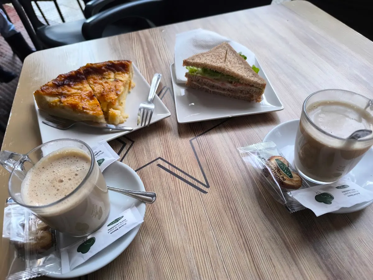 Café con porciones de tarta y sándwich en una mesa de Maiatza Kafetegia