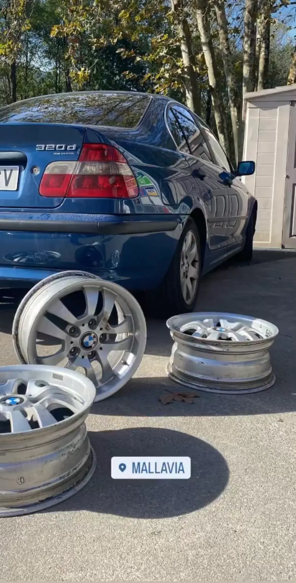 Llantas junto a un coche azul con la ubicación de Mallabia Motorsport.