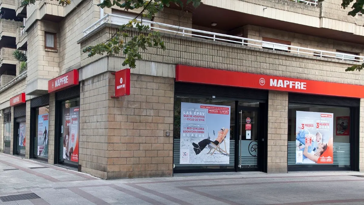 Exterior de la oficina Mapfre en una esquina de Durango, con rótulos rojos y escaparates.