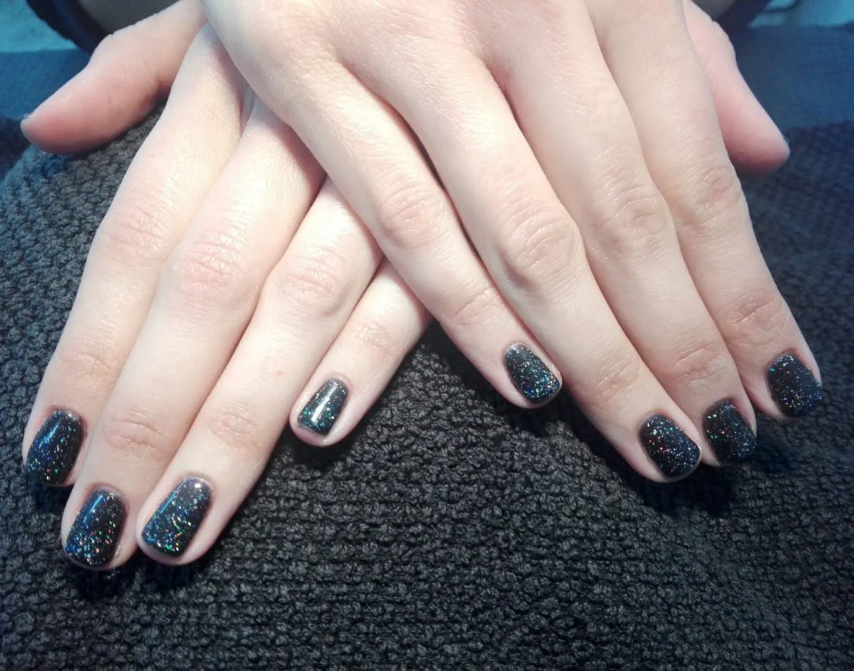 Manos con uñas pintadas con esmalte oscuro brillante en Maria Suarez Dermoestetica