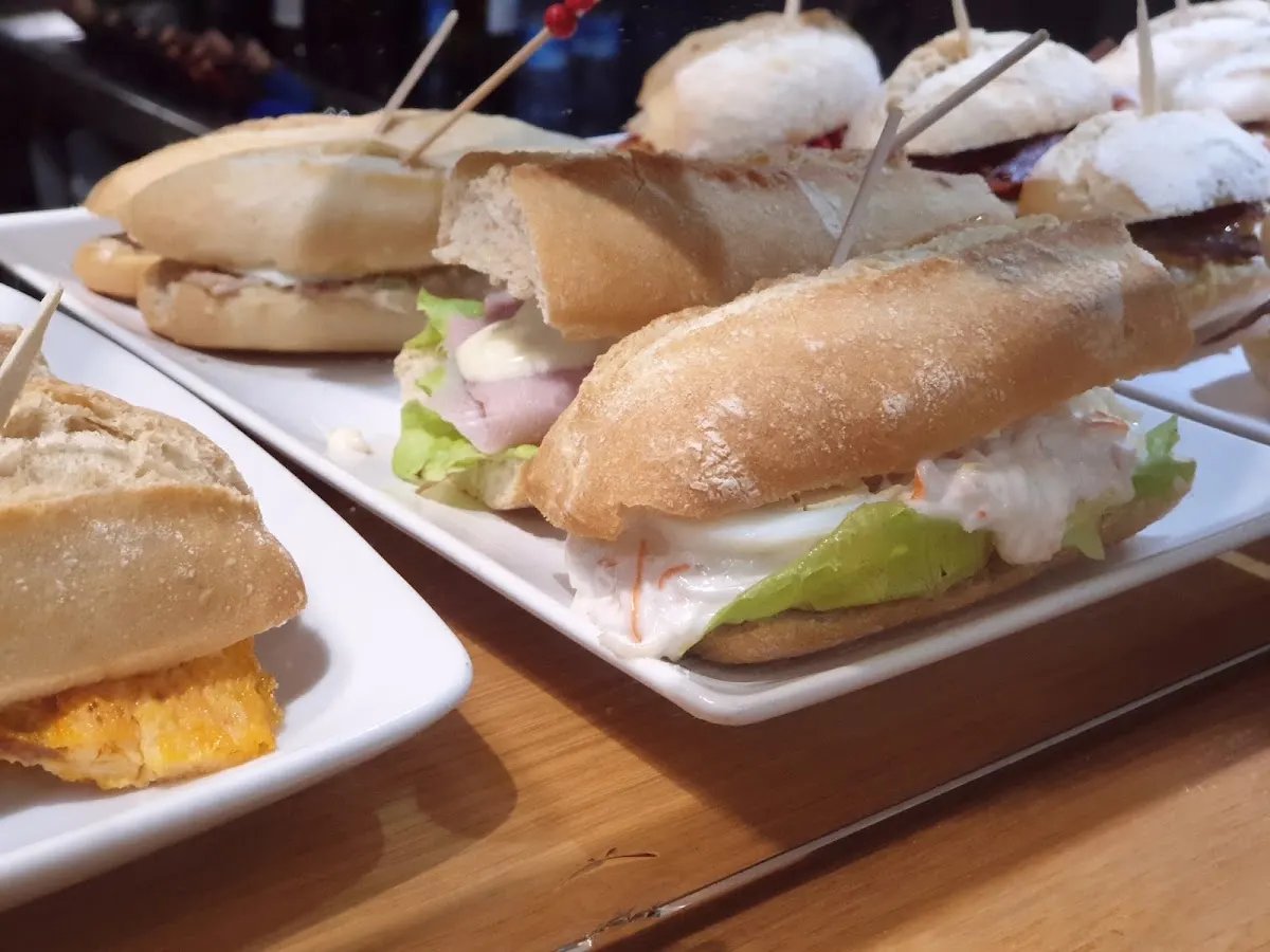 Varios bocadillos y pintxos servidos en platos sobre una mesa de madera.