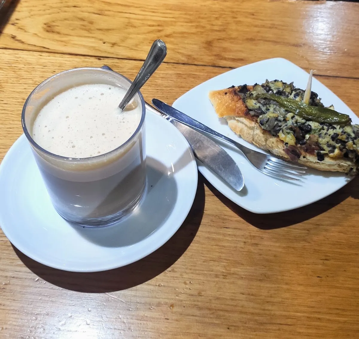 Café y pintxo de verduras servidos sobre una mesa de madera.