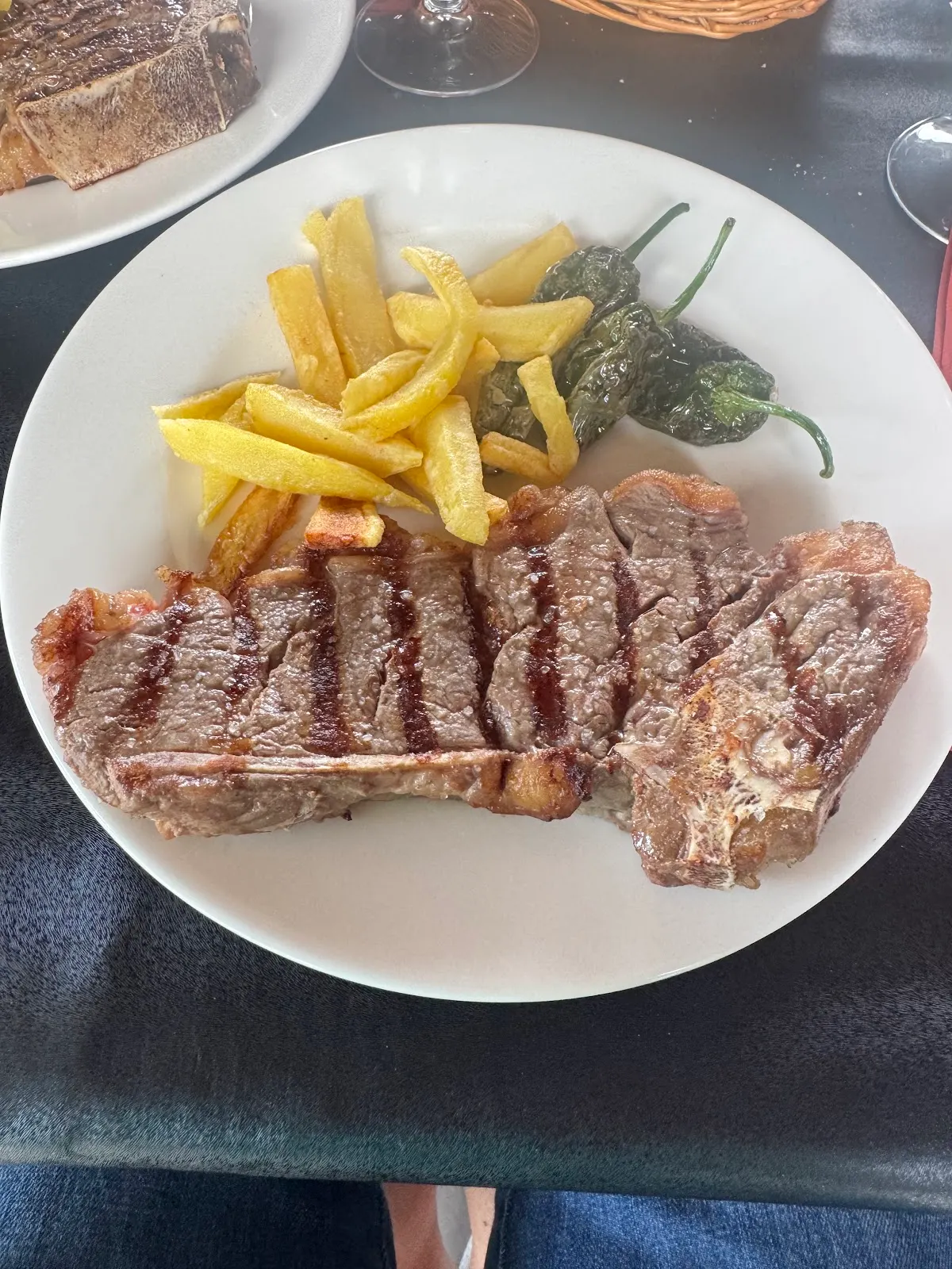 Plato de carne con patatas fritas y pimientos en Milikuena Jatetxea.