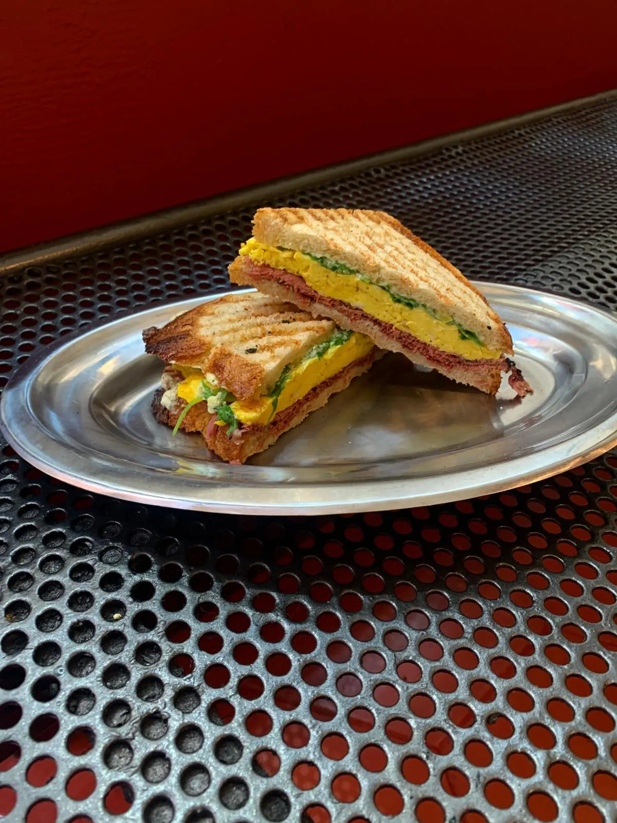 Sándwich tostado servido en un plato metálico en Miñe Taberna.