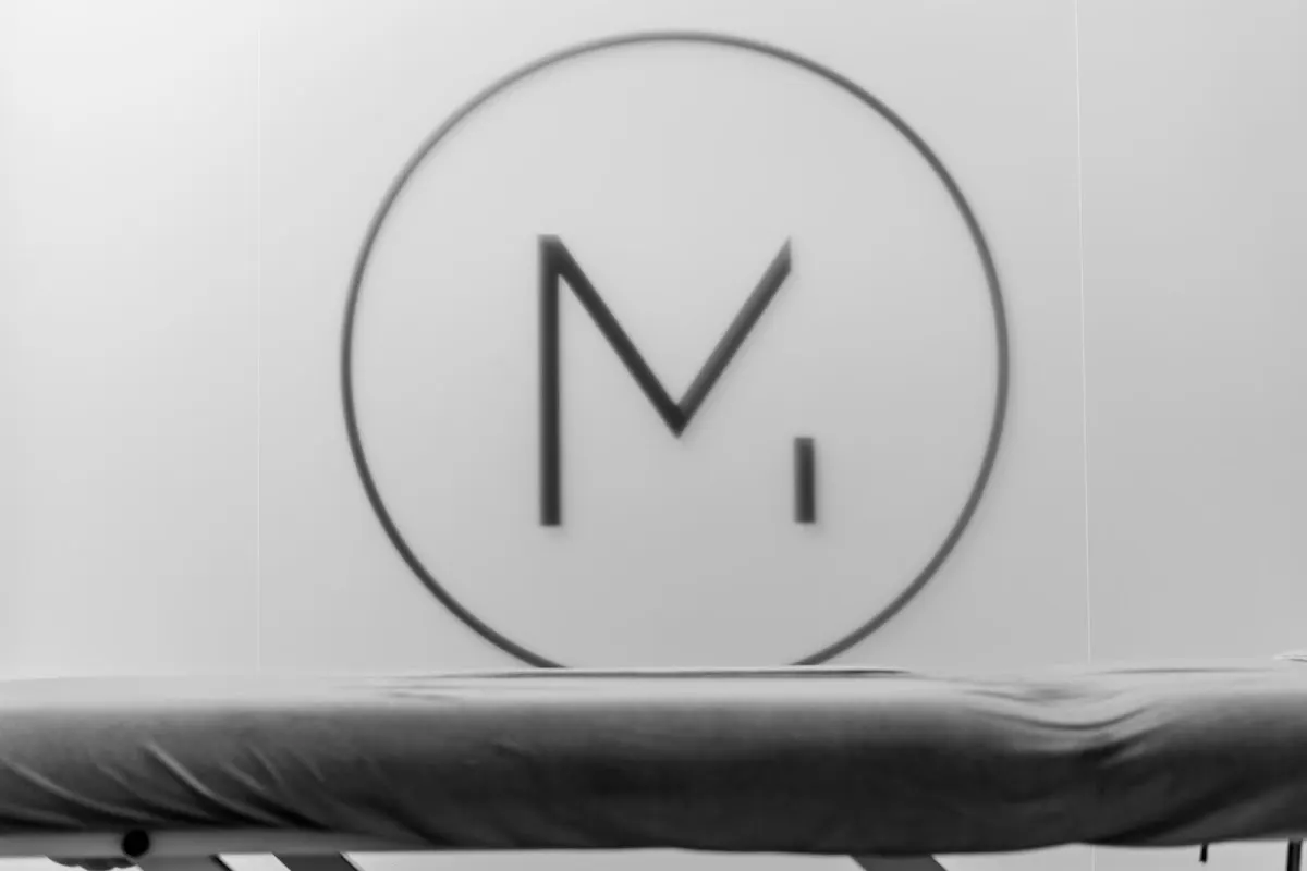 Logotipo circular de MUBA Fisioterapia Avanzada en una pared.