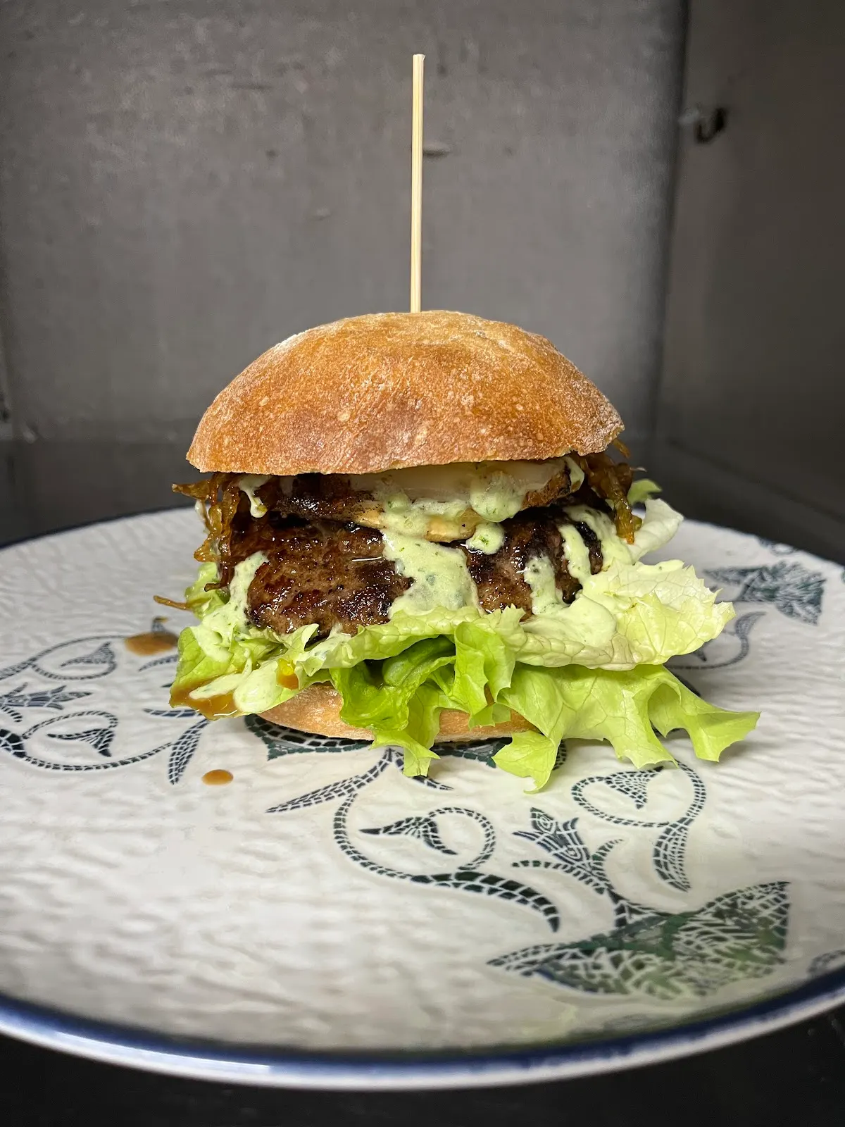 Hamburguesa con lechuga y salsa servida en un plato.