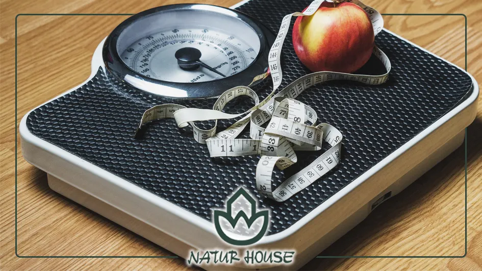 Imagen de una báscula, una manzana y una cinta métrica con el logotipo de Naturhouse