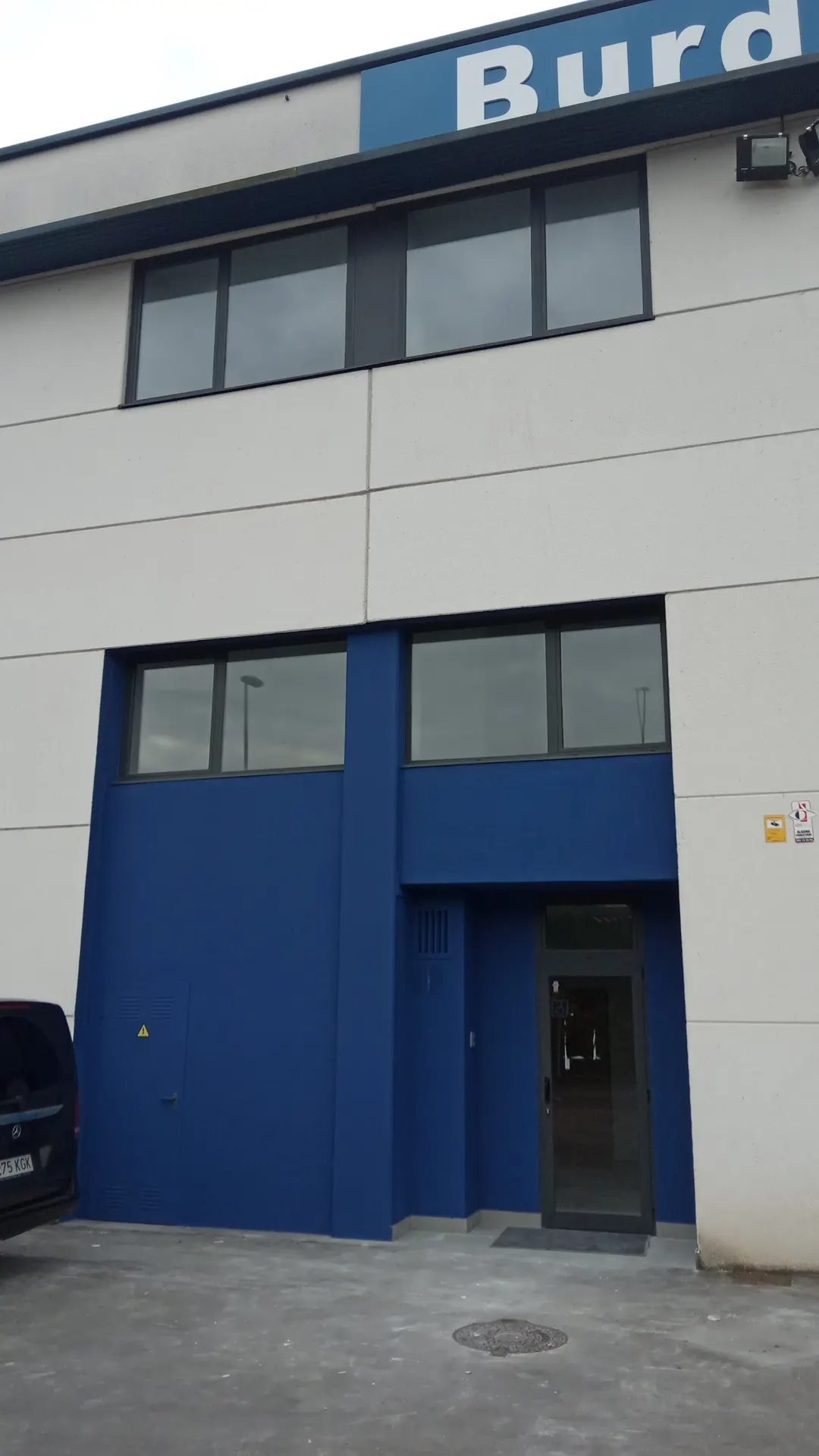 Entrada de una nave con rótulo de empresa en la fachada.