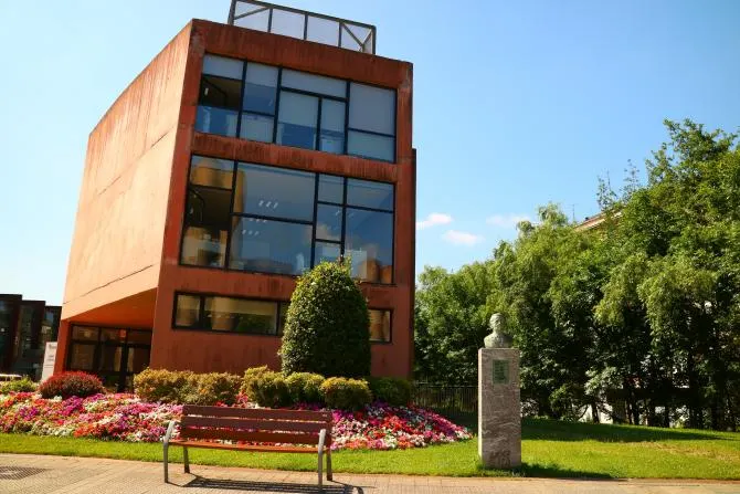 Edificio de fachada rojiza junto a una zona ajardinada, en una imagen asociada a O.D.P. Inmobiliaria.