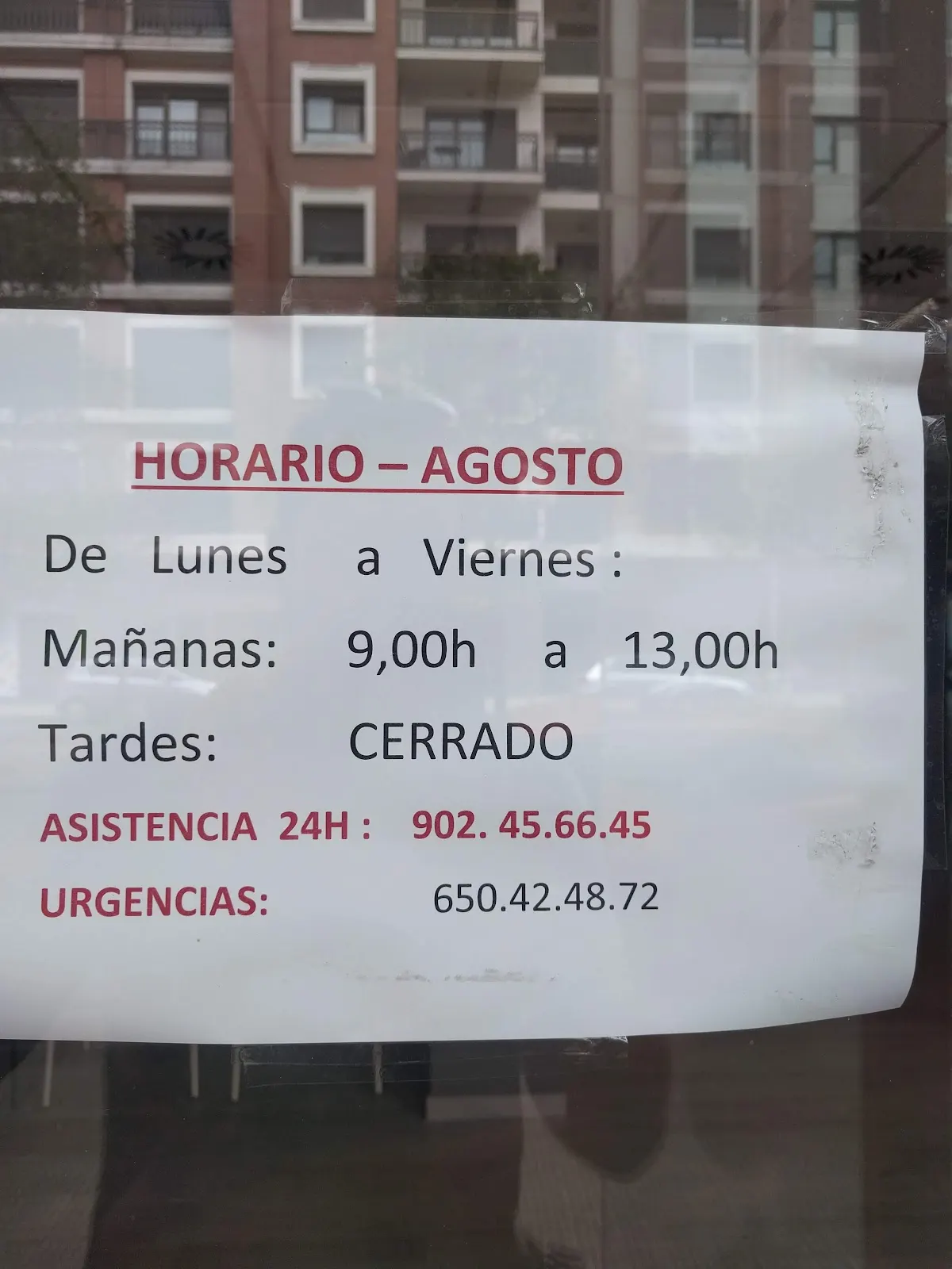 Cartel con el horario de agosto y teléfonos de asistencia y urgencias