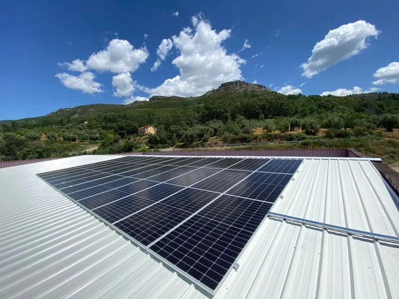 Paneles solares instalados sobre la cubierta de un edificio, con montes al fondo.
