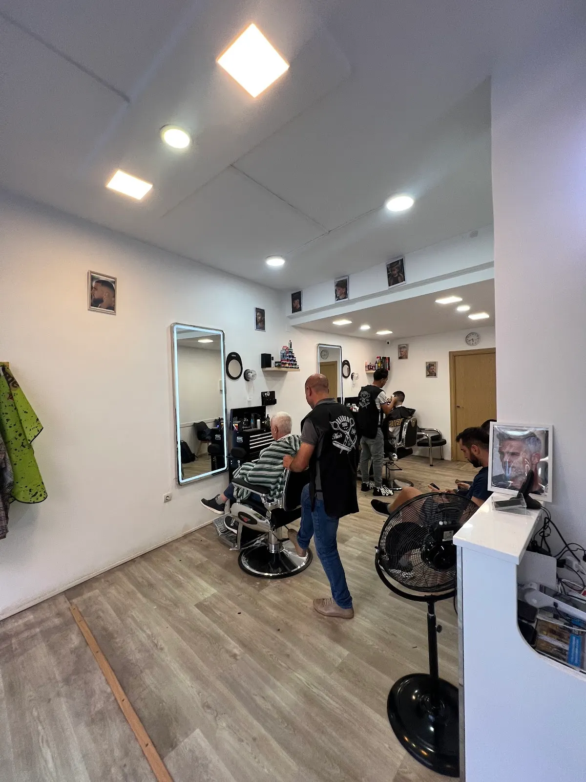 Interior de PELUQUERIA ABDEL BARBER SHOP con puestos de corte y clientes.