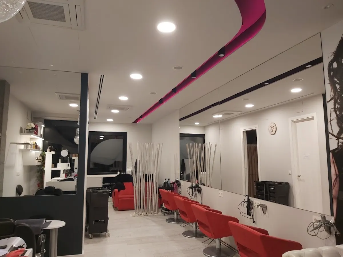Interior de Peluquería Bea Garcia Ileapaindegia, con sillones rojos frente a los espejos.