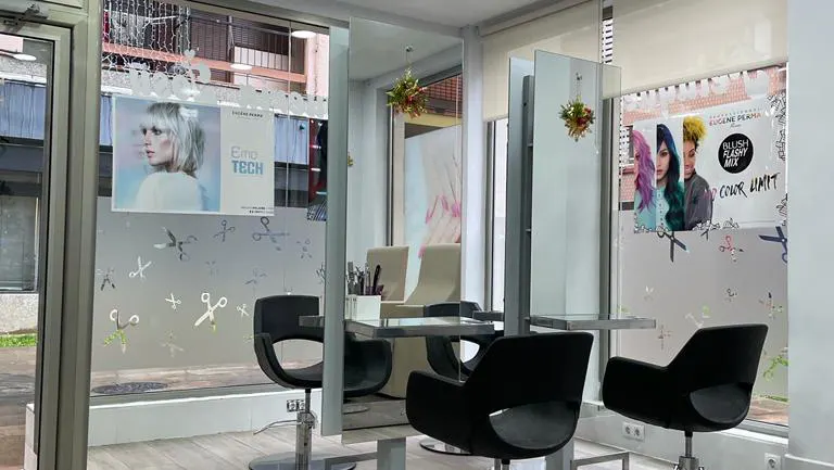 Interior de Peluquería Josy con puestos de trabajo y sillones frente al escaparate.