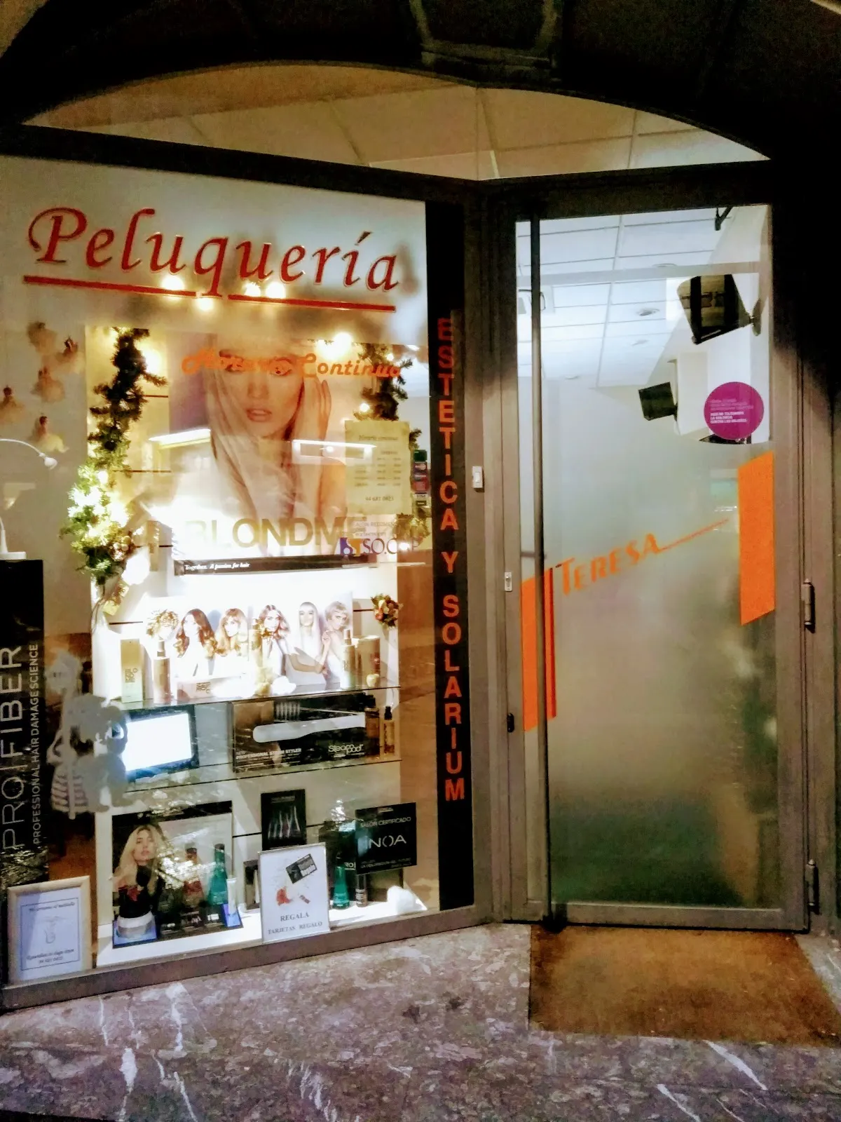 Escaparate de Peluquería Teresa Aguado en Durango, con productos y carteles de peluquería y estética.