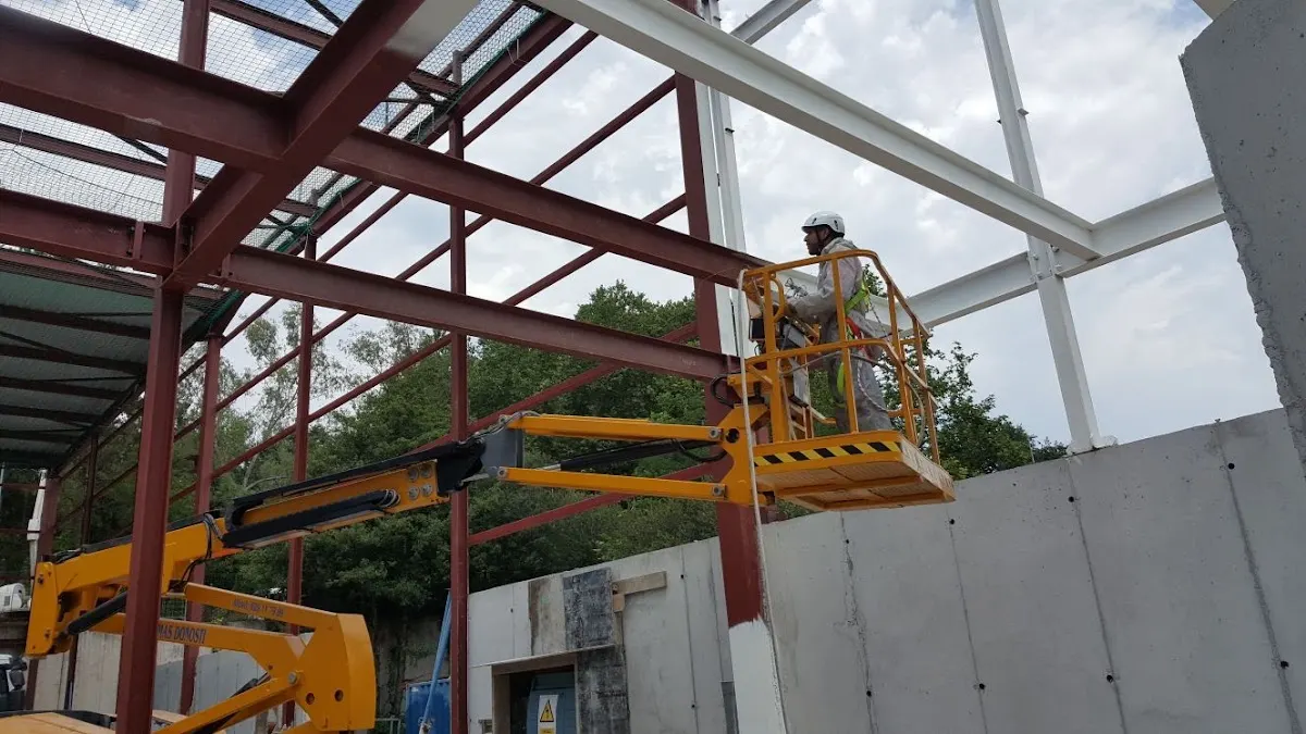 Trabajador en una plataforma elevadora junto a una estructura metálica
