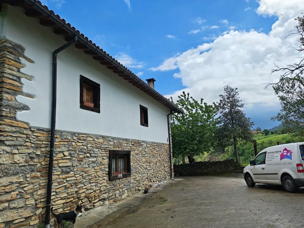 Exterior de una vivienda con revestimiento de piedra y una furgoneta de Pinturas y decoración Martín S.L.