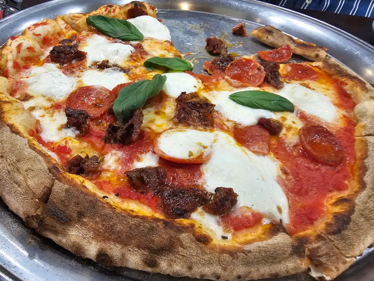 Pizza de Pizzería Tivoli con queso, tomate, embutidos y albahaca