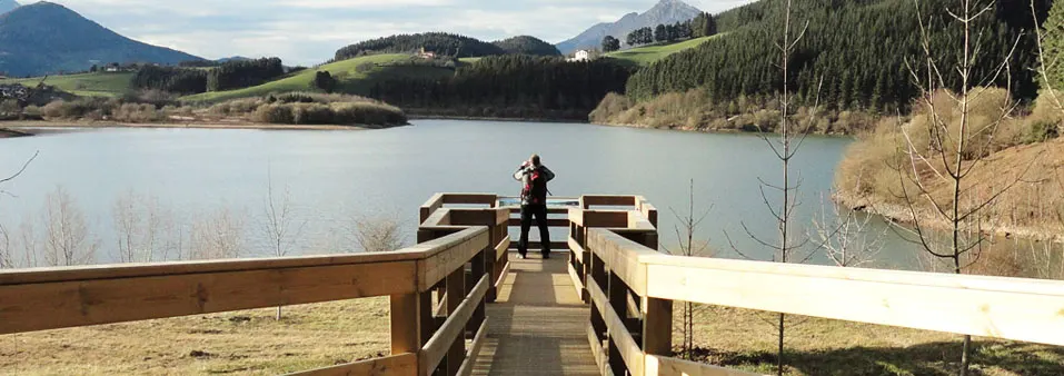 Pasarela de madera junto a un embalse en un entorno montañoso