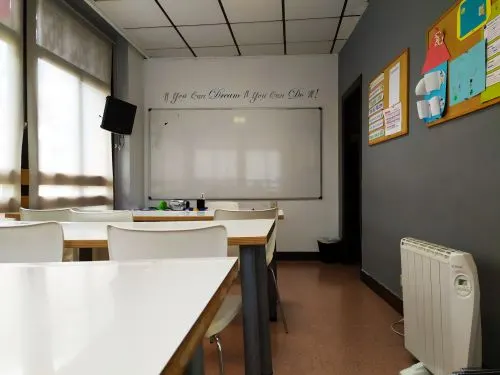 Aula de Quality English con mesas, sillas y pizarra blanca