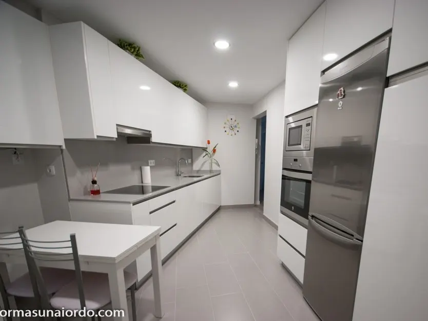 Cocina reformada con muebles blancos y electrodomésticos integrados, imagen de Reformas Unai Ordoñez.
