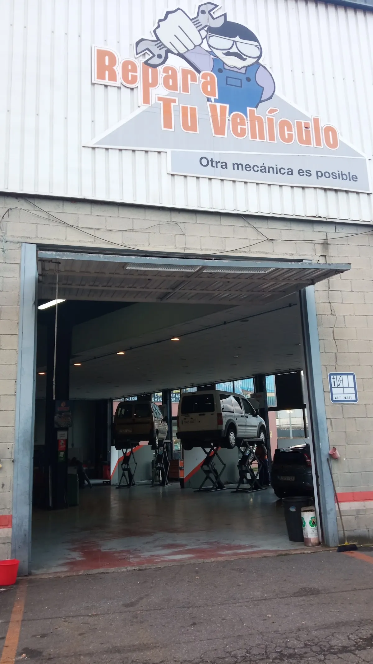 Entrada del taller Repara Tu Vehículo, con varios vehículos sobre elevadores.
