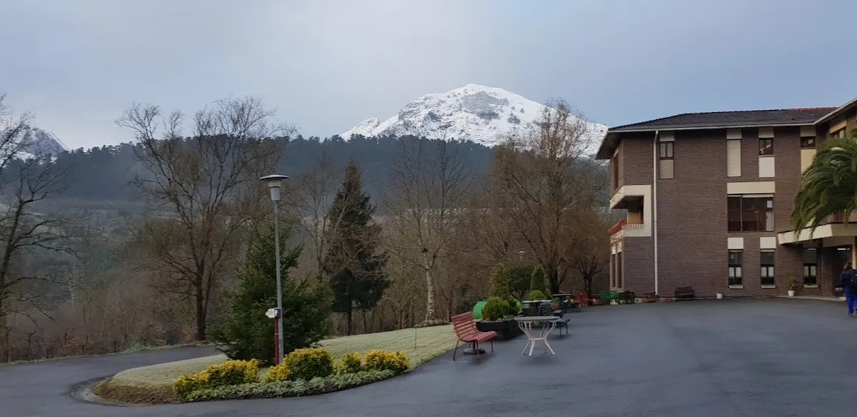 Residencia Atxarte junto a un entorno arbolado y una montaña nevada.
