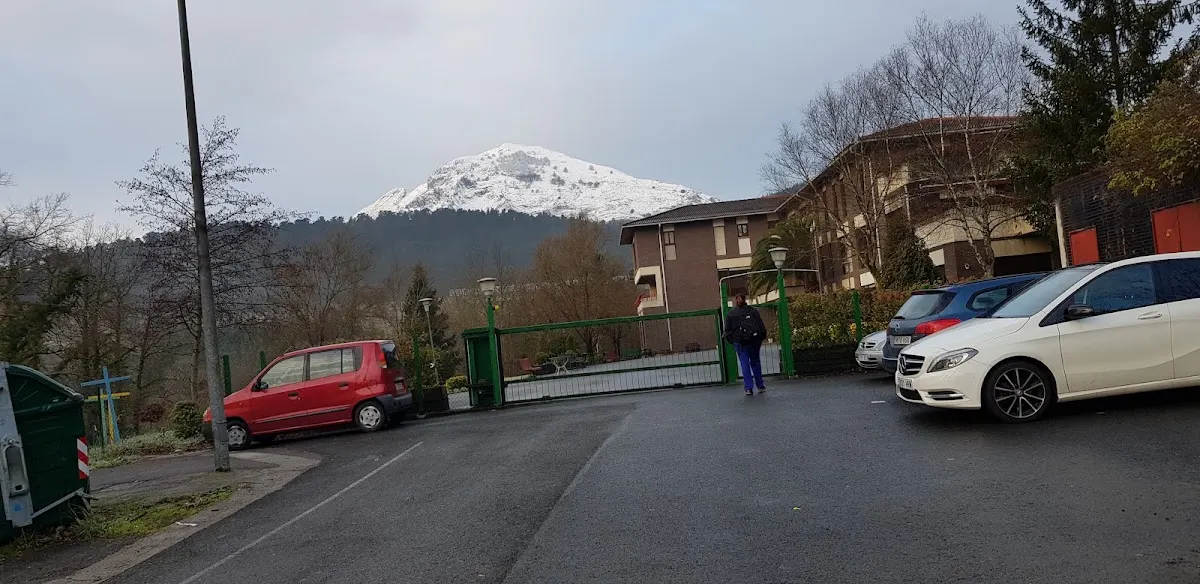 Acceso y aparcamiento de la Residencia Atxarte, con una montaña al fondo.