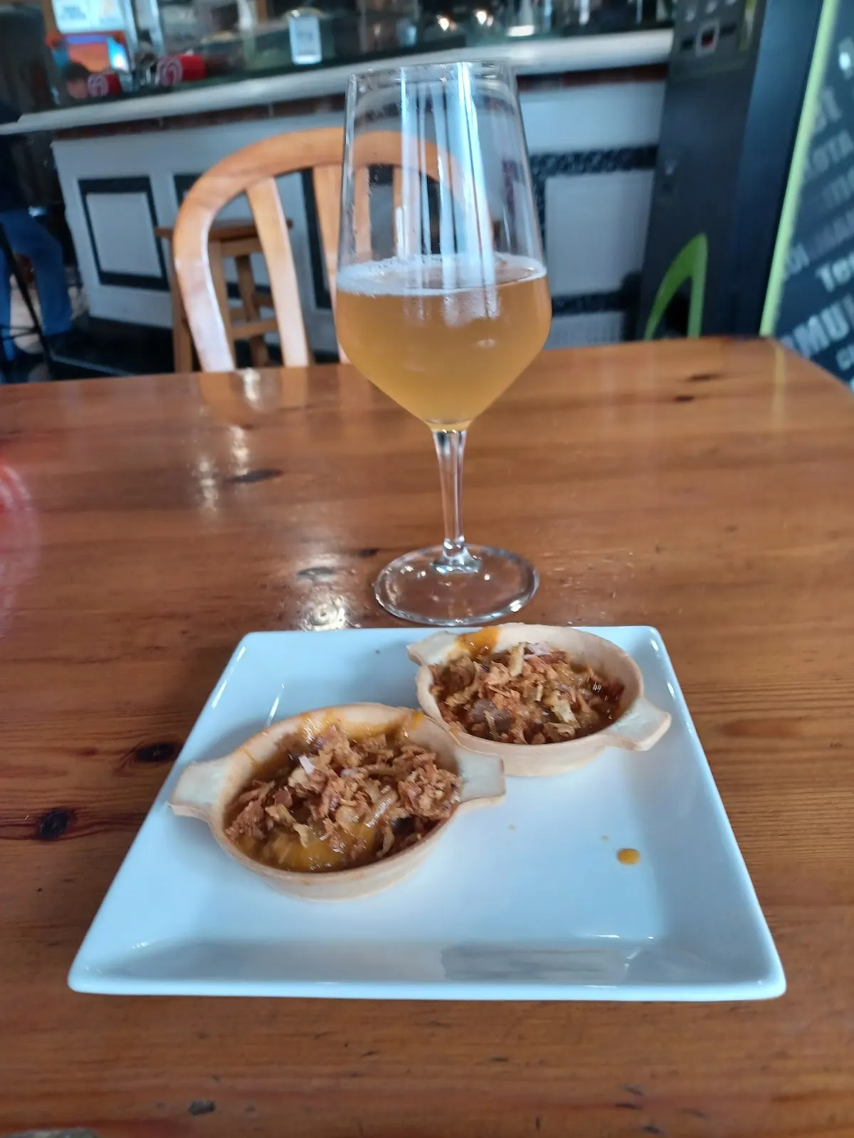 Plato de tapas y copa en una mesa de madera de Barnebide Jatetxea.