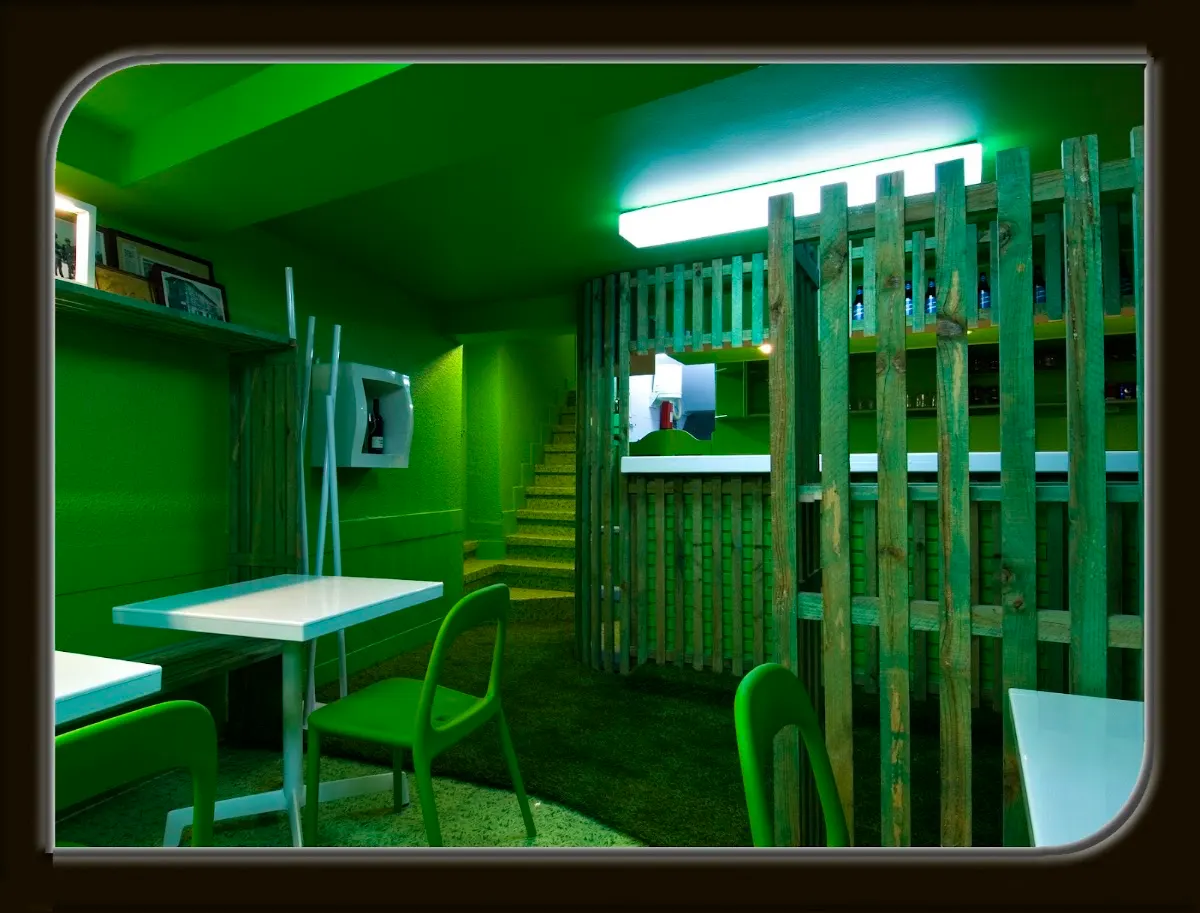 Interior de El Pastor del Gorbea, con mesas y mobiliario verde separados por una estructura de listones de madera.