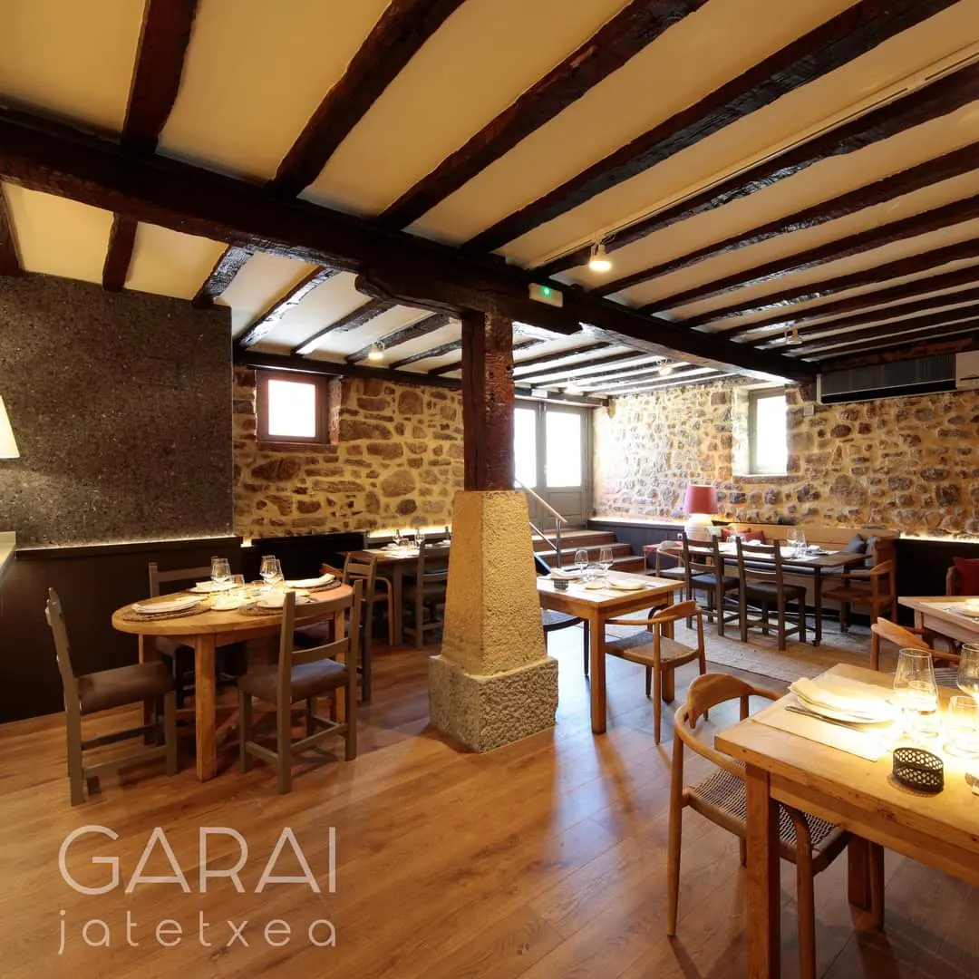 Comedor de estilo rústico de Garai Jatetxea, con mesas de madera y paredes de piedra.