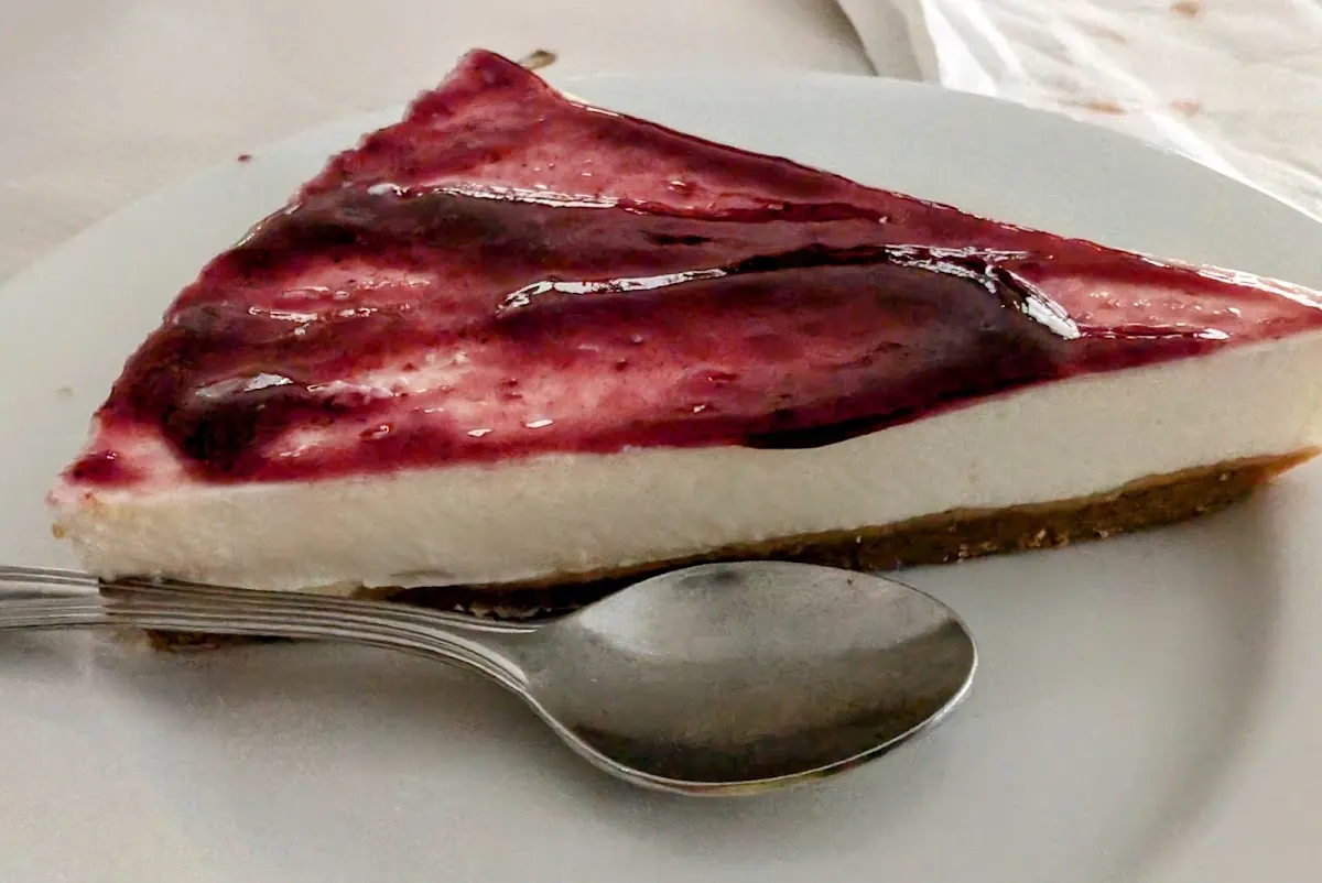 Porción de tarta con cobertura de frutos rojos en un plato.