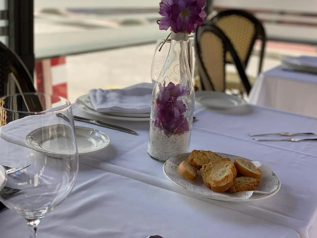 Mesa de Restaurante Gaztelua con pan, copas y un jarrón con flores