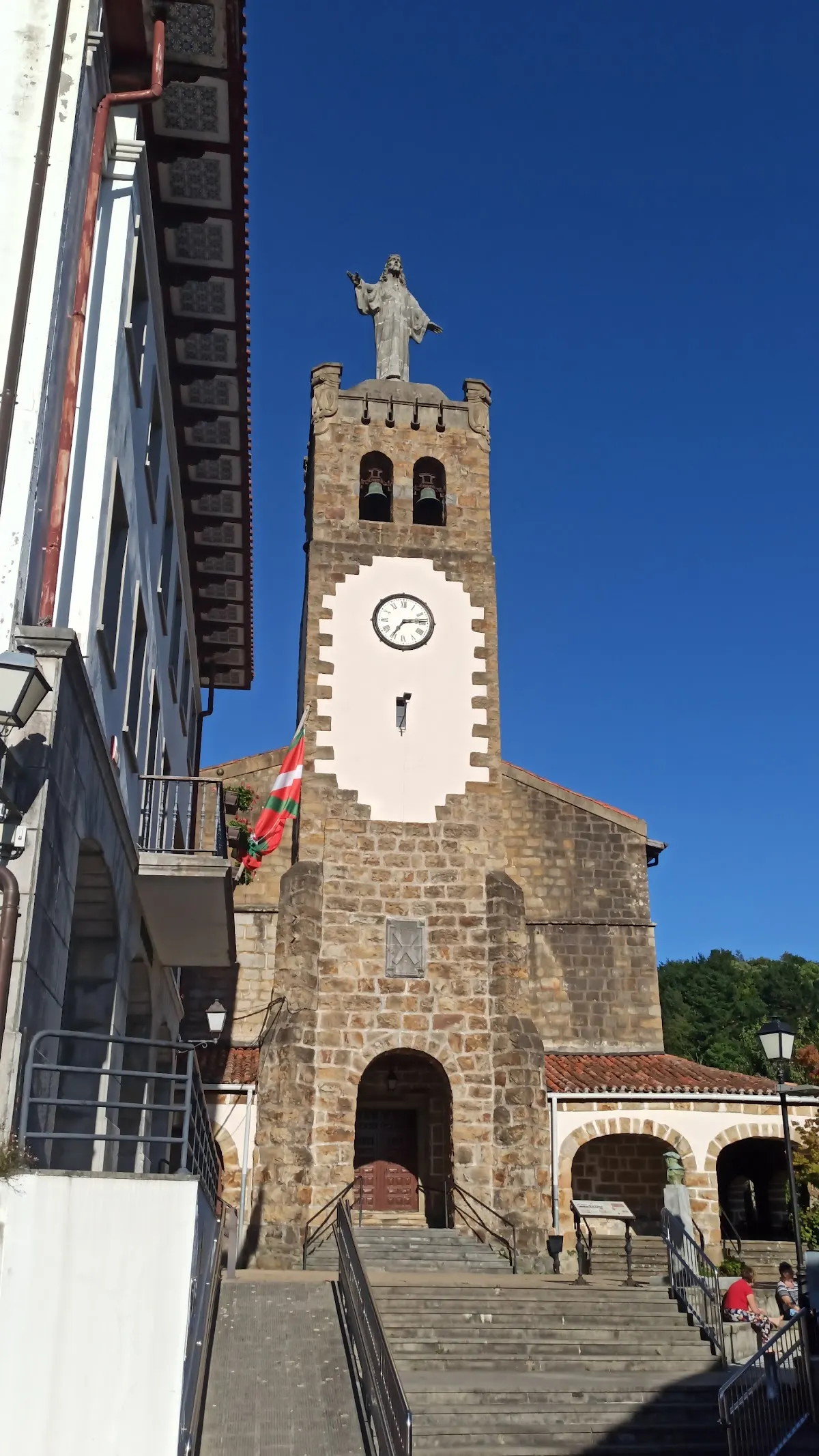 Iglesia de piedra con torre y reloj en una plaza.