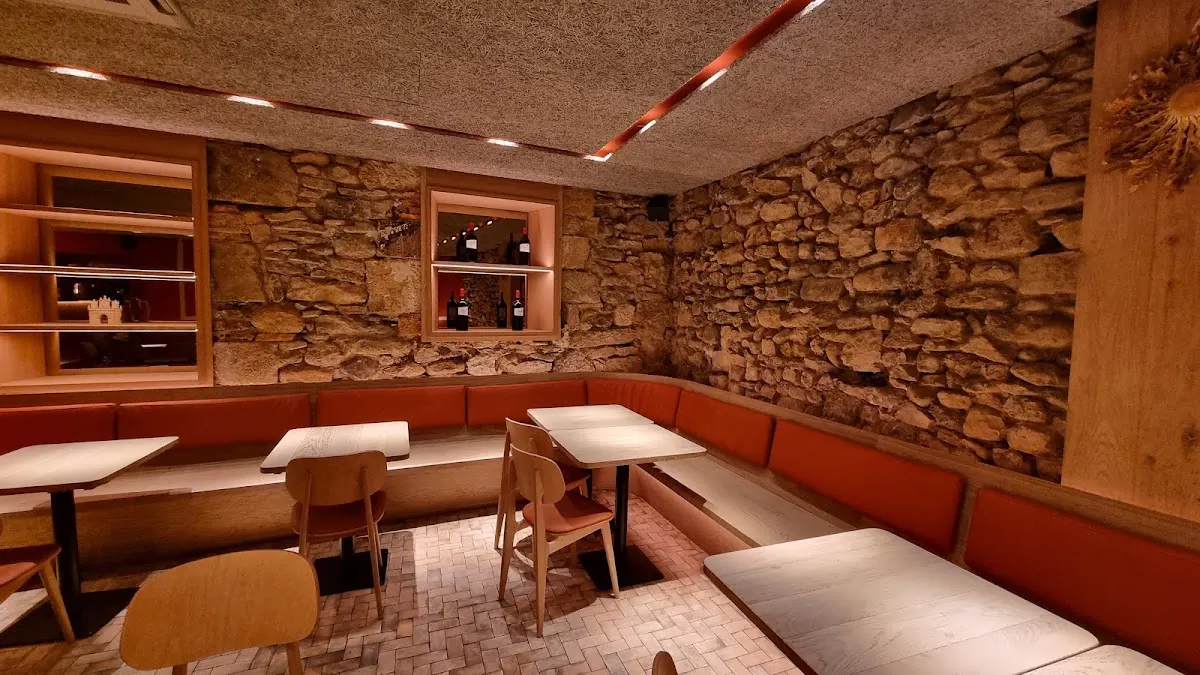 Comedor de Restaurante Txanto con bancos corridos, mesas y paredes de piedra.