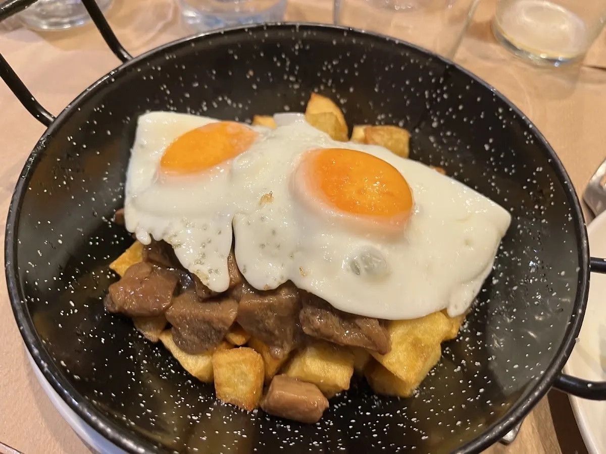Huevos fritos con patatas y otros ingredientes en una sartén de Restaurante Txanto.
